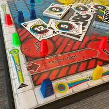 Load image into Gallery viewer, Close up on the 3d printed replacement pieces. Each color is a different shape. There are scattered cards with transparent braille on them in the background.