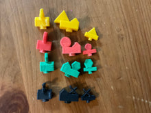 Load image into Gallery viewer, All the types of player pieces. Each color has a distinct shape on them, red circles, black xs, yellow triangles and green hexagons