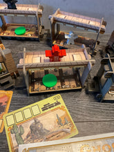 Load image into Gallery viewer, An action shot of a red meeple on top of the train. The red meeple has an R on it to distinguish it from the other colors.