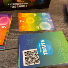 Load image into Gallery viewer, A close up on the gene pool cards. They have braille on each edge. The part facing away from the user is 'upright' and players rotate the card as they gain or lose their gene pool just like print players do. A pile of trait cards is in the foreground with a QR code. Although the text of the card is in braille on the cards, sometimes it is reworded to fit on the card. The QR code has the full text of the card in the original wording.