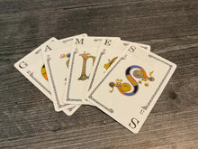 Load image into Gallery viewer, Cards spelling "Games" are laid out. Transparent braille shows the letter and point value of the cards.