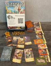 Load image into Gallery viewer, The box of Citadels along with all the different types of cards. Cards have the gameplay information on them in transparent braille.