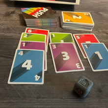 Load image into Gallery viewer, Another shot of the cards. The die is closer to the camera and has the color green showing on it indicated by a  braille g