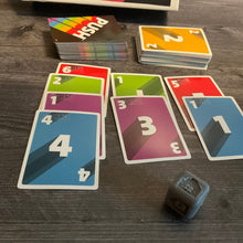 Load image into Gallery viewer, Another shot of the cards. The die is closer to the camera and has the color green showing on it indicated by a braille g