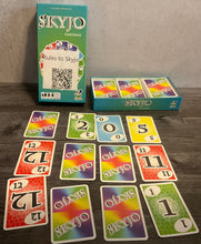 Load image into Gallery viewer, The box with a 3x4 grid of cards set up in front of it. All the cards have transparent braille on them.