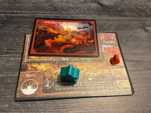 Load image into Gallery viewer, A close up on the desert landscape. The bury feature is being used so a monster card is on it.