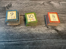 Load image into Gallery viewer, Three stacks of favor tiles. All of them have transparent braille stickers on them.