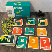 Load image into Gallery viewer, Scale of 1 to T-Rex game laid out. Replacement tokens for the bad tokens are shown and all the different decks are sorted.