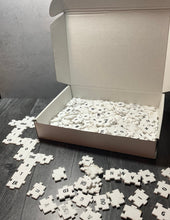 Load image into Gallery viewer, A picture showing the open box with a collection of tiles in front of it. Some of the tiles are forming a crossword grid.