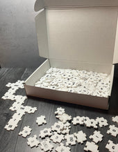 Load image into Gallery viewer, A picture showing the open box with a collection of tiles in front of it. Some of the tiles are forming a crossword grid.