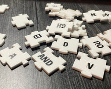 Load image into Gallery viewer, A close up on the tiles showing the braille and the large print on them. Each tile fits together with puzzle piece like tabs so that they will not move apart.