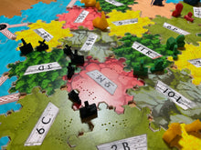 Load image into Gallery viewer, Close up on black settlements. You can see the braille on the printed pieces and the replacement numbers for board randomization fit snuggly into the slots on the tiles.