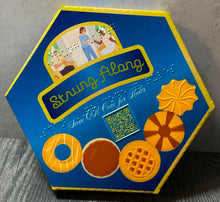 Load image into Gallery viewer, A close up on the Strung Along box. It is printed to resemble a cookie tin because obviously that is where sewing stuff is stored.