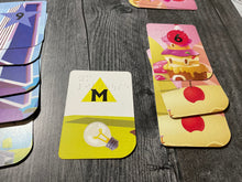 Load image into Gallery viewer, A close up of the towers that a player is currently building. The yellow cards are lighthouse themed and the red cards are candy themed