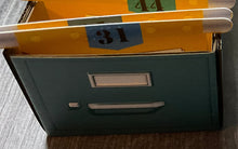 Load image into Gallery viewer, A close up shot of the folders in a filing cabinets. The cabinet itself is tactile with a 'handle' and a 'label'