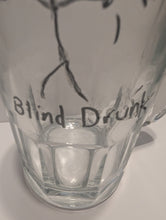 Load image into Gallery viewer, A close-up of a clear glass mug with a black hand-drawn tactile stick figure and the words 'Blind Drunk' written on it in both print and braille.