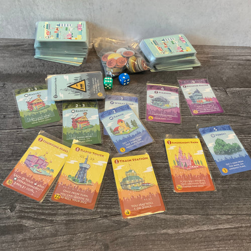 The cards from Machi Koro with transparent braille stickers on them.