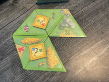 Load image into Gallery viewer, A close up of a partially built town. 2 completed task cards are on the board. Players can read the word horse in braille next to Conrad the Confused's horse. A partially built tournament is in the corner of the tiles.
