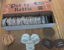 Load image into Gallery viewer, Pot to Kettle box is on the table with a few of the two types of cards stacked below it.
